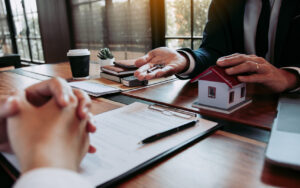 Hand of real estate agent passes the key to new homeowners in office with buyer house concept.