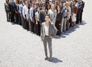 Portrait of confident businesswoman with team of business people in background